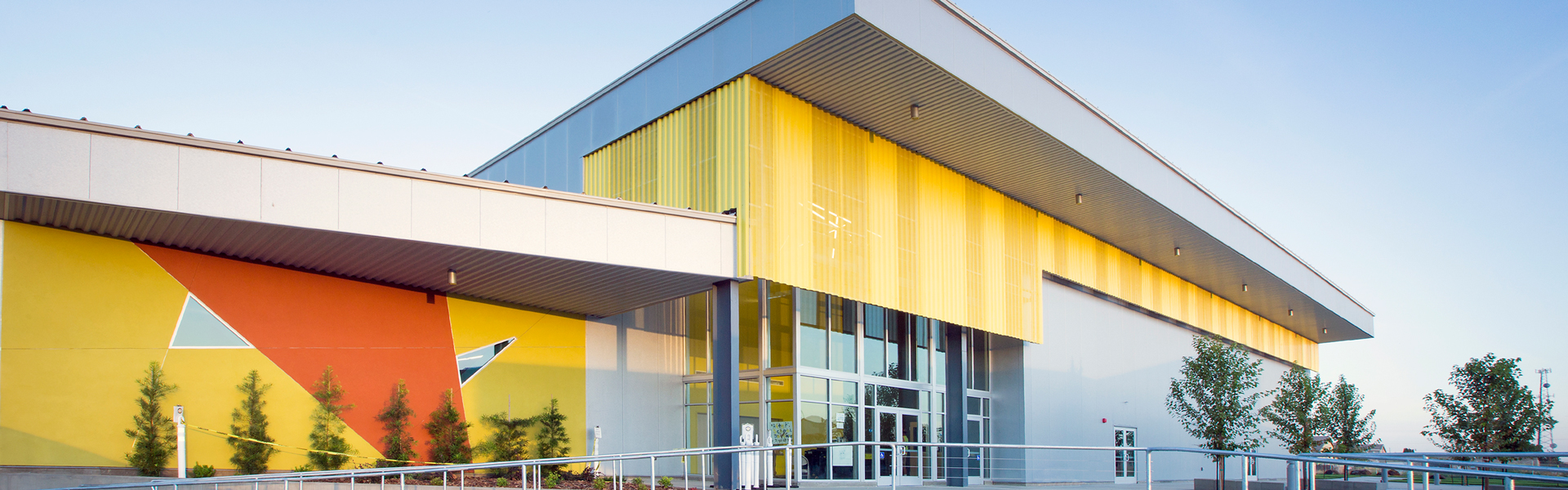 Twin Rivers Charter School exterior with colorful panel facade, large glass entry and metal roof overhang